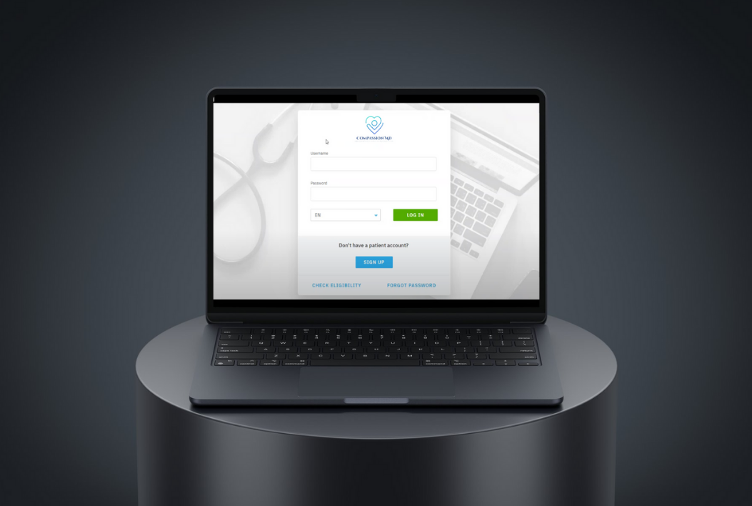 A sleek laptop showing the Compassion MD login screen.