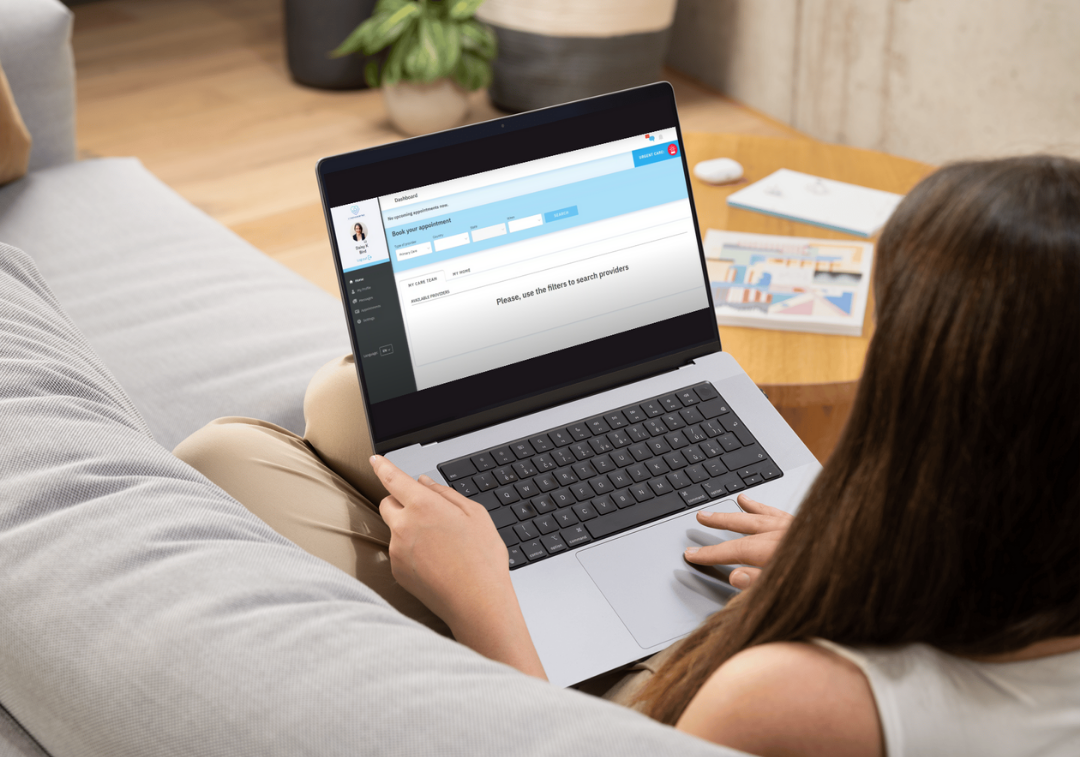 A person using the Compassion MD app on a laptop in a comfortable home setting.