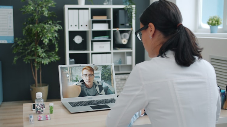 A doctor providing virtual care through a laptop.