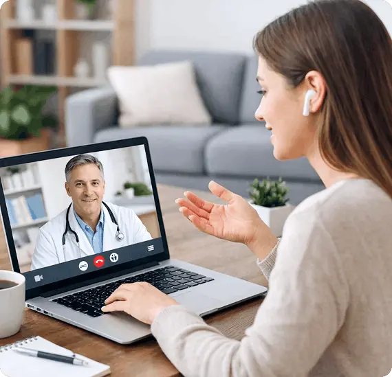 A women sitting on her drawing room and having a conversation through her laptop with a doctor.