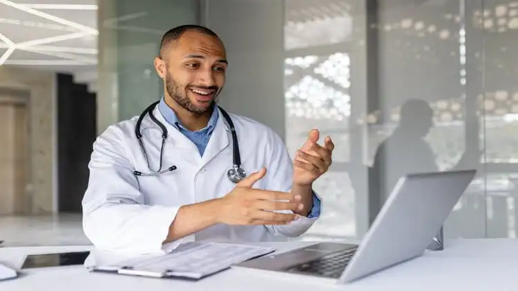 A male doctor is having a video confarence using a laptop